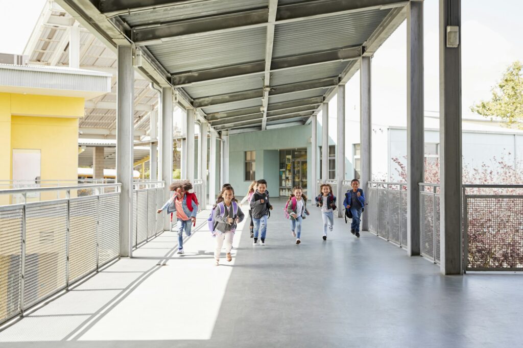 Young school kids running on a walkway in their school